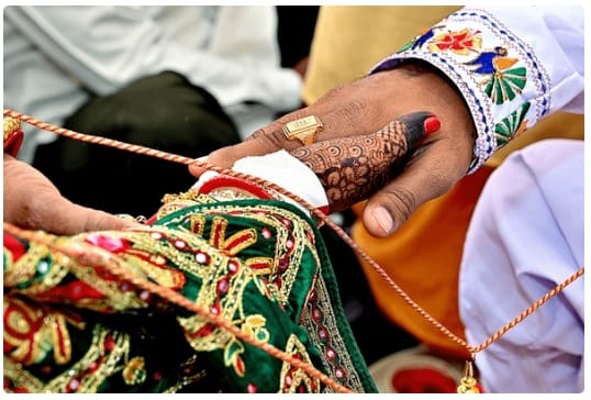 The priest ties the groom’s shawl with the bride’s saree,